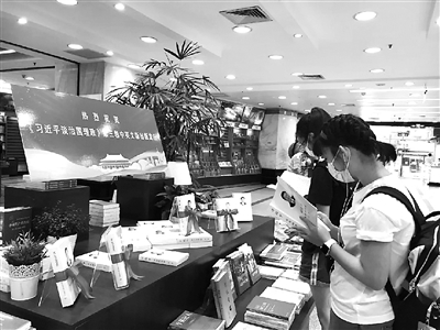 圖為讀者近日在上海書城設(shè)置的《習(xí)近平談治國理政》第三卷專架展臺前閱讀。  外文出版社供圖
