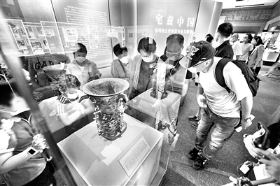 距今3000多年的青銅何尊，器內(nèi)底部有122字銘文。其中的“宅茲中國”，是關于“中國”一詞最早的文字記載，彰顯了中華文化源遠流長的獨特魅力。圖為2020年8月18日，觀眾在國家博物館“宅茲中國——寶雞出土青銅器與金文精華”展上觀看展出的何尊。 （圖片來源：視覺中國）